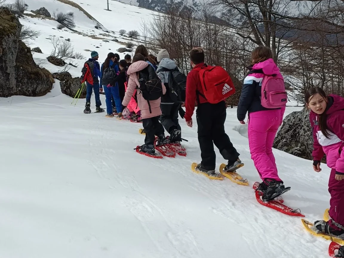 Un gruppo scolastico cammina con le ciaspole sulla neve